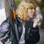 image for Bosnian woman, holding an AK-47 rifle and smoking a cigarette as she waits for a funeral service, 1992.