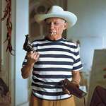 image for Pablo Picasso wearing a hat and holding a revolver &amp; holster given to him by Gary Cooper - Cannes, 1958
