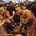 image for A monk prays for an elderly man who had died suddenly while waiting for a train in China.