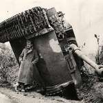image for A British soldier hiding from the rain under an overturned Tiger tank. Italy 1944