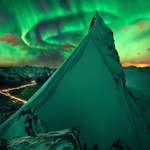 image for Aurora over Norway. Notice someone standing on the peak with the best view.