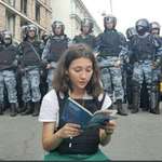 image for Russian teenager Olga Misik reading the Russian constitution while being surrounded by armed Russian riot police is one of the most powerful images of bravery against injustice and oppression I have seen. Reminds me of the Tiananmen Square Tank Man.
