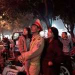 image for A Vietnamese police officer watching Lunar New Year firework display with his wife and daughter who visited him during his shift last night