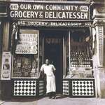image for Harlem grocer standing in front of his store, 1937.