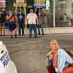 image for Muslim woman taking a photo in front of anti Islam protesters.