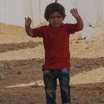 image for A Syrian child mistakes a camera, held by a member of the Red Cross, for a gun