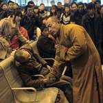 image for A Buddhist Monk praying and holding the hand of a man who died sitting at a train station in China