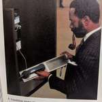 image for Smoking gentleman using an acoustic coupler to send an email with a payphone. Early 1980s.