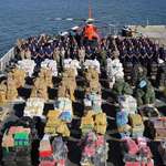 image for U.S. Coast Guards pose next to 28,000 lbs of cocaine and 11,000 pounds of marajuana they seized.