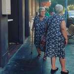 image for Two older ladies passing by one another dressed the same with one eyeing the other