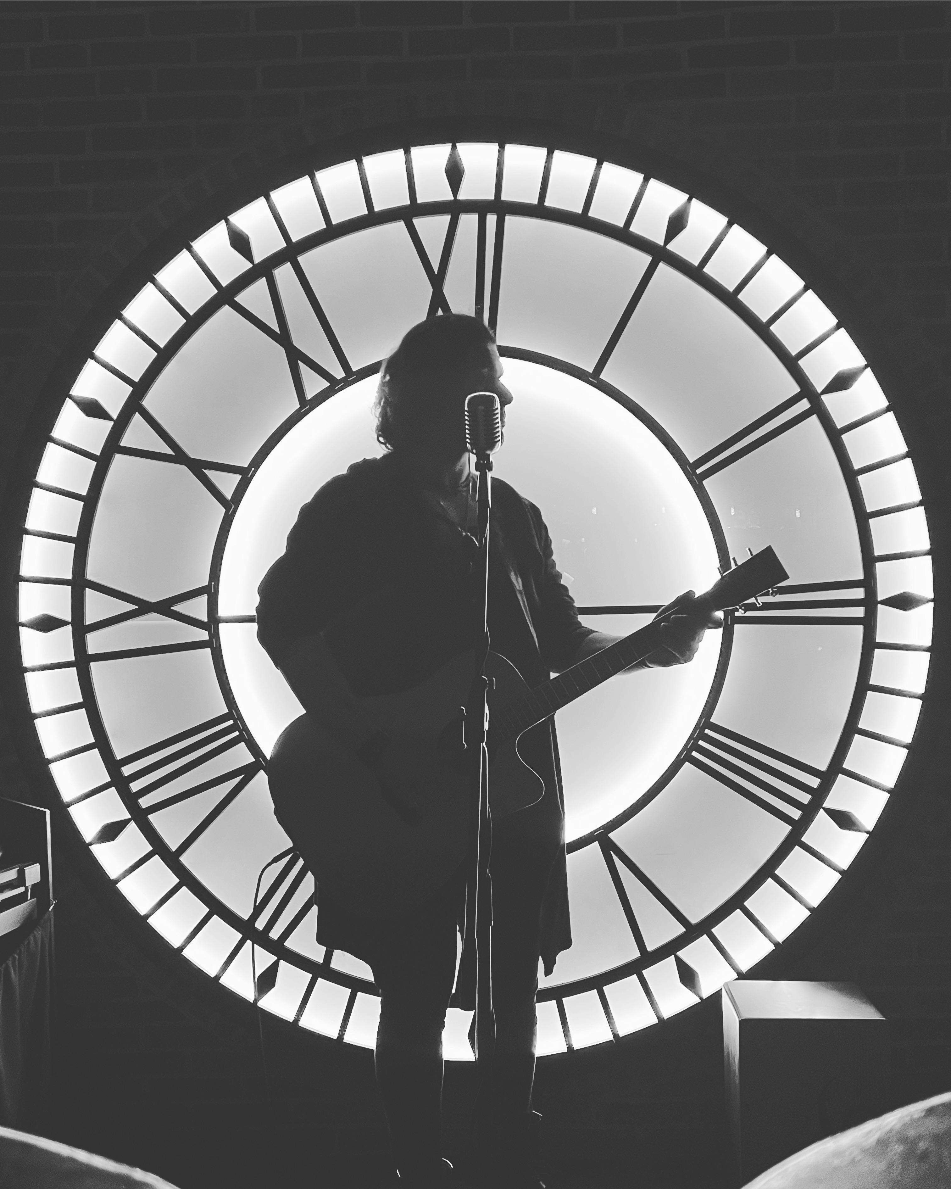image showing ITAP of my friend playing a gig in front of a back-lit clock dial in Malta.