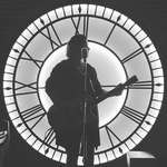 image for ITAP of my friend playing a gig in front of a back-lit clock dial in Malta.