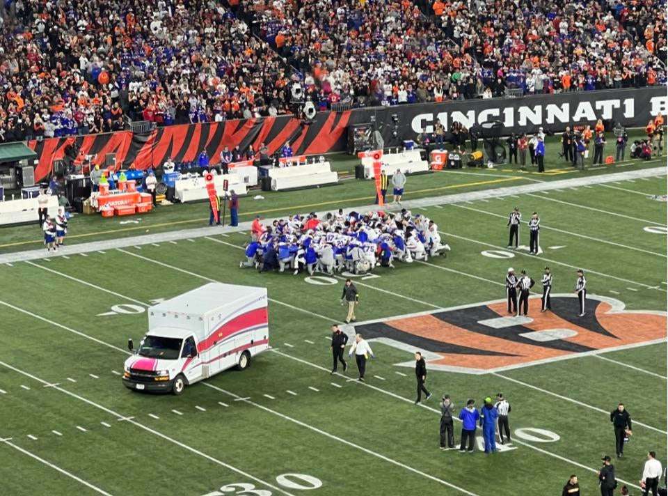 image showing Entire Bills team in prayer as Damar Hamlin leaves the field in an ambulance.