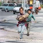 image for A boy carrying his dog while crossing the infamous “Sniper Alley” - April 1995