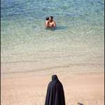 image for A woman watches her son and husband go for a swim in the ocean