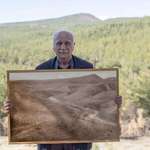 image for Man posing with picture of forest he restored