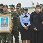image for A guard holding a picture of Samarn Kunan, 38, a diver who died saving 13 lives in a flooded cave