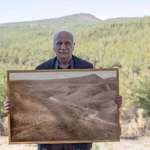 image for Man poses with an old photo of a forest he restored