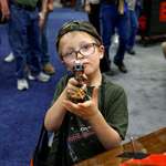 image for A 6-year-old from Indiana trying out a gun during the NRA's annual convention in 2023.