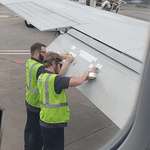 image for Applying tape to the plane's wings right before the flight.