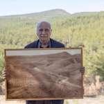 image for Man posing with picture of the forest he restored