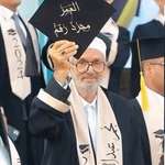 image for 80-years Iraqi man graduating university holding his cap with "Age is Just a Number" written on it.