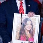 image for Trump smiling with a picture he autographed of Laken Riley, that he misspelled.