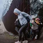 image for Migrants cross through a gap in the U.S.-Mexico border fence in Jacumba Hot Springs, Calif., on Dec.