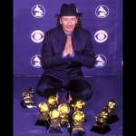 image for Carlos Santana in 2000 next to all the Grammys he won in one night for “Smooth”/“Supernatural”