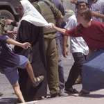image for A picture taken seconds before settlers kick and pull the head covering off a woman in Hebron, Pal.