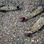 image for People on boats collect recyclable plastics from the heavily polluted Citarum River in Indonesia