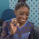 image for Simone Biles showing off a diamond-encrusted goat necklace after winning her 6th Olympic gold.