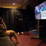 image for US Presidential Candidate Kamala Harris watches running mate Tim Walz speak as she sits backstage