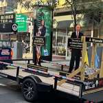 image for Cardboard Trump and Putin ride in a trailer through downtown Boston