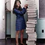 image for Margaret Hamilton stands next to code she wrote by hand for the Apollo Project.
