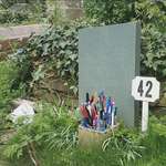 image for Douglas Adams' grave has a bouquet of pens and a small towel laid out for him.