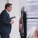 image for Mike Lindell carrying a paper calling for martial law in the name of national security.