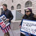 image for Laid off USAID employee holds up poignant warning sign