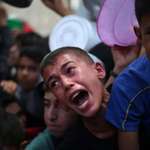 image for Palestinian children wait for food at a distribution point in Nuseirat, in the central Gaza Strip