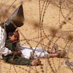image for Iraqi prisoner comforts his frightened child through barbed wire –World Press Photo of the Year 2003
