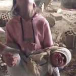 image for A sister carries her infant brother, their family's sole survivors, from their bombed home in Gaza.