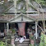 image for [OC] A dilapidated home with an American flag draped over the front door.