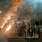 image for A munition explodes as law enforcement confronts protesters at night [OC]