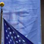 image for Trump menacingly over the US flag from his banner at the department of Justice