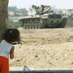 image for A Palestinian girl watches an Israeli tank in Rafah refugee camp, Gaza. 📸 Abid Katib, 10/11/2003
