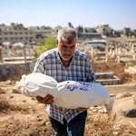 image for A relative of the Masri family carries their youngest daughter, Amira
