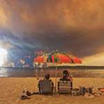 image for Beach goers in Lacanau, France, watch as clouds of smoke rise into the sky from a wildfire